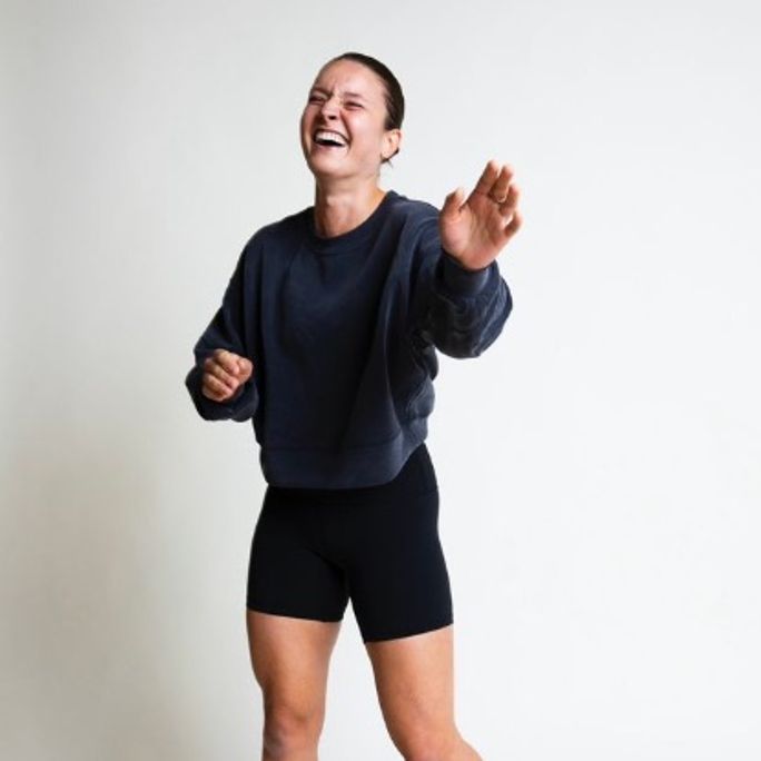 Photo of athletic woman in running attire, smiling and laughing to camera.