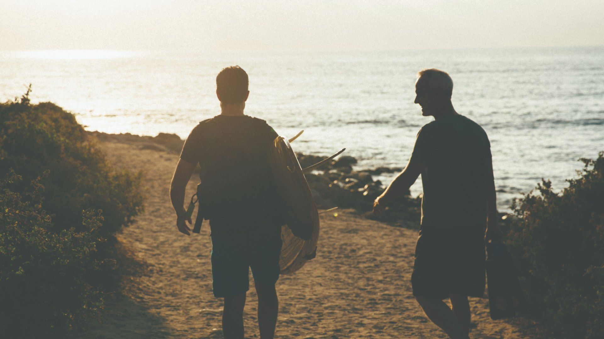 Two men carrying surf boards by the shore