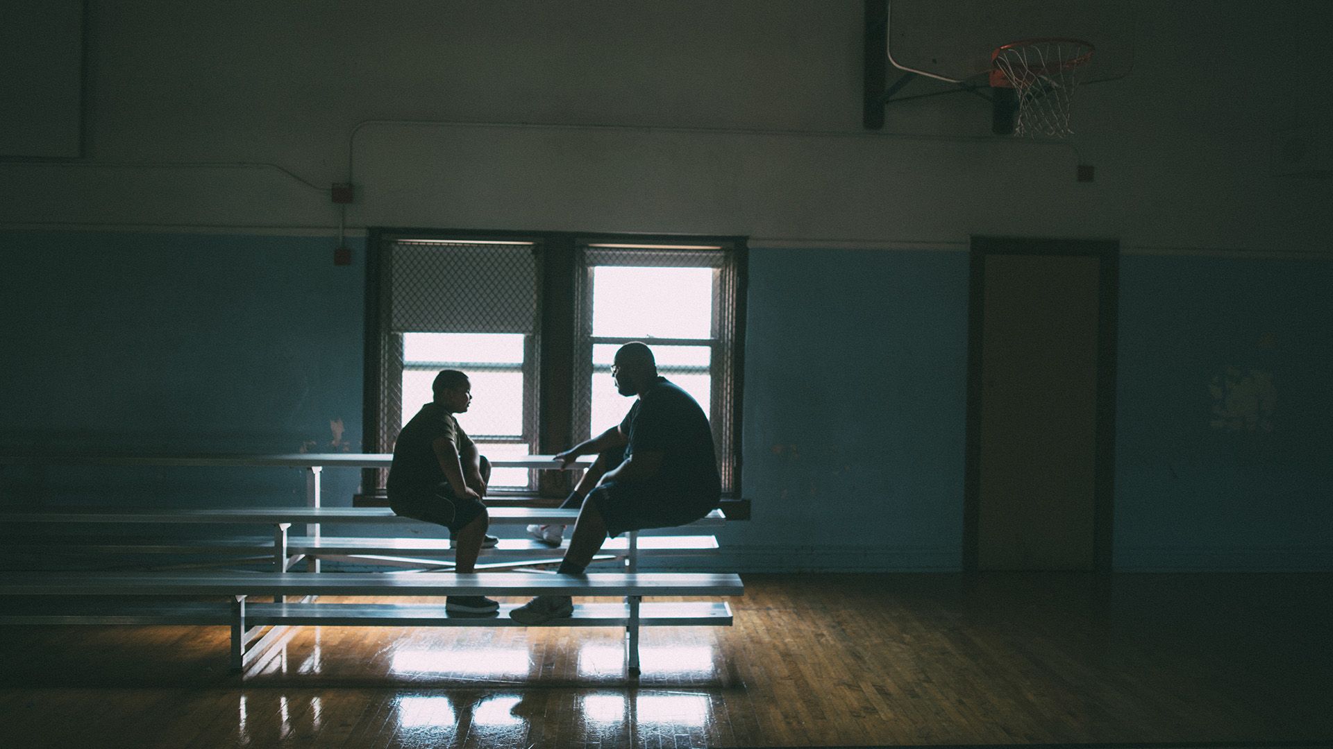 Two people having a serious discussion in a school gym.