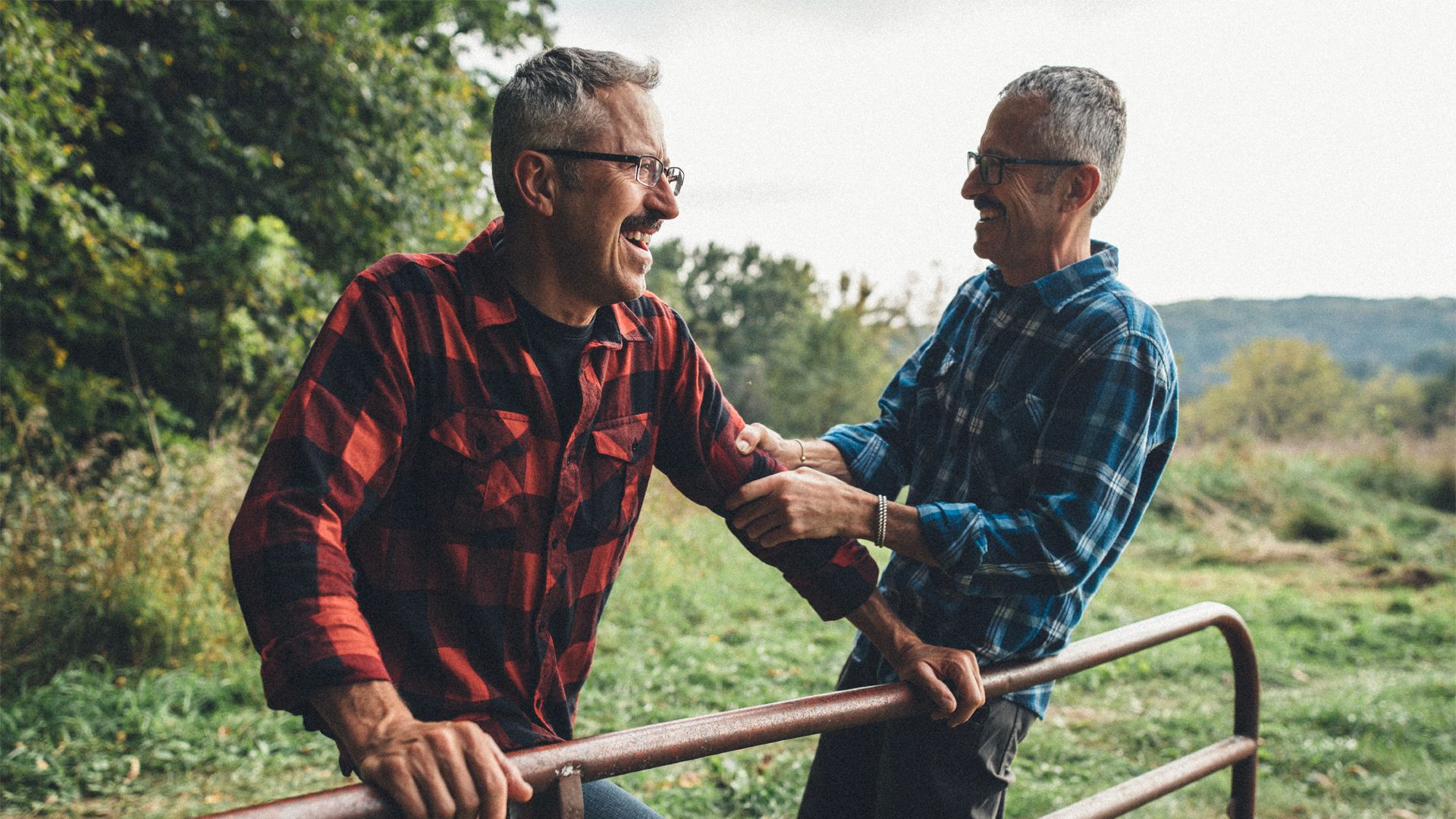 Twin brothers laughing with one another in a rural setting