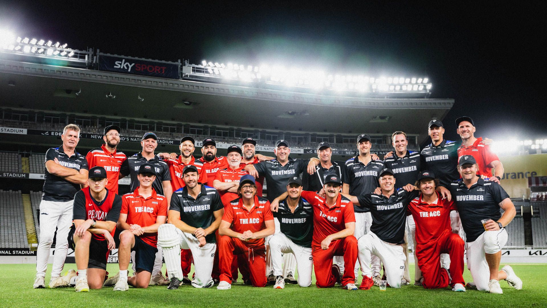 Two cricket teams at large sports ground stand together and pose for post match photograph