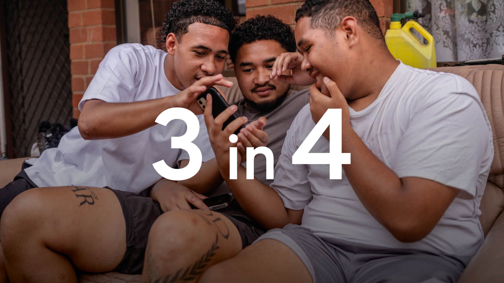 Photo of three seated young men looking at a phone screen. The numeral "62%" is superimposed in white text.