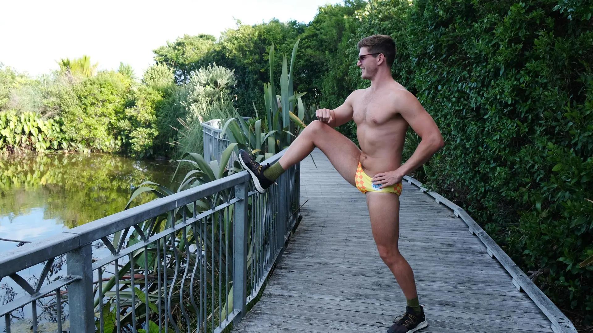 Athletic young man stretching while wearing astonishingly bright speedos