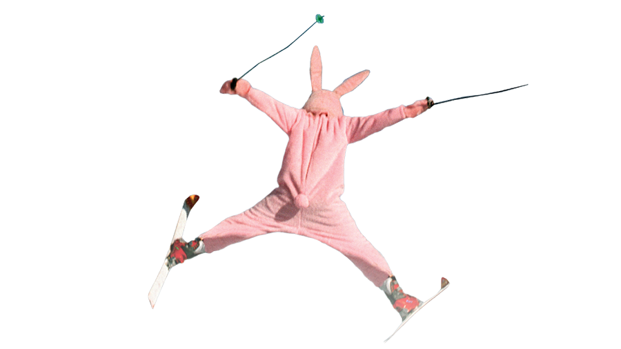 Photo of a person in a rabbit costume, donning skis and ski poles, in mid aerial leap.