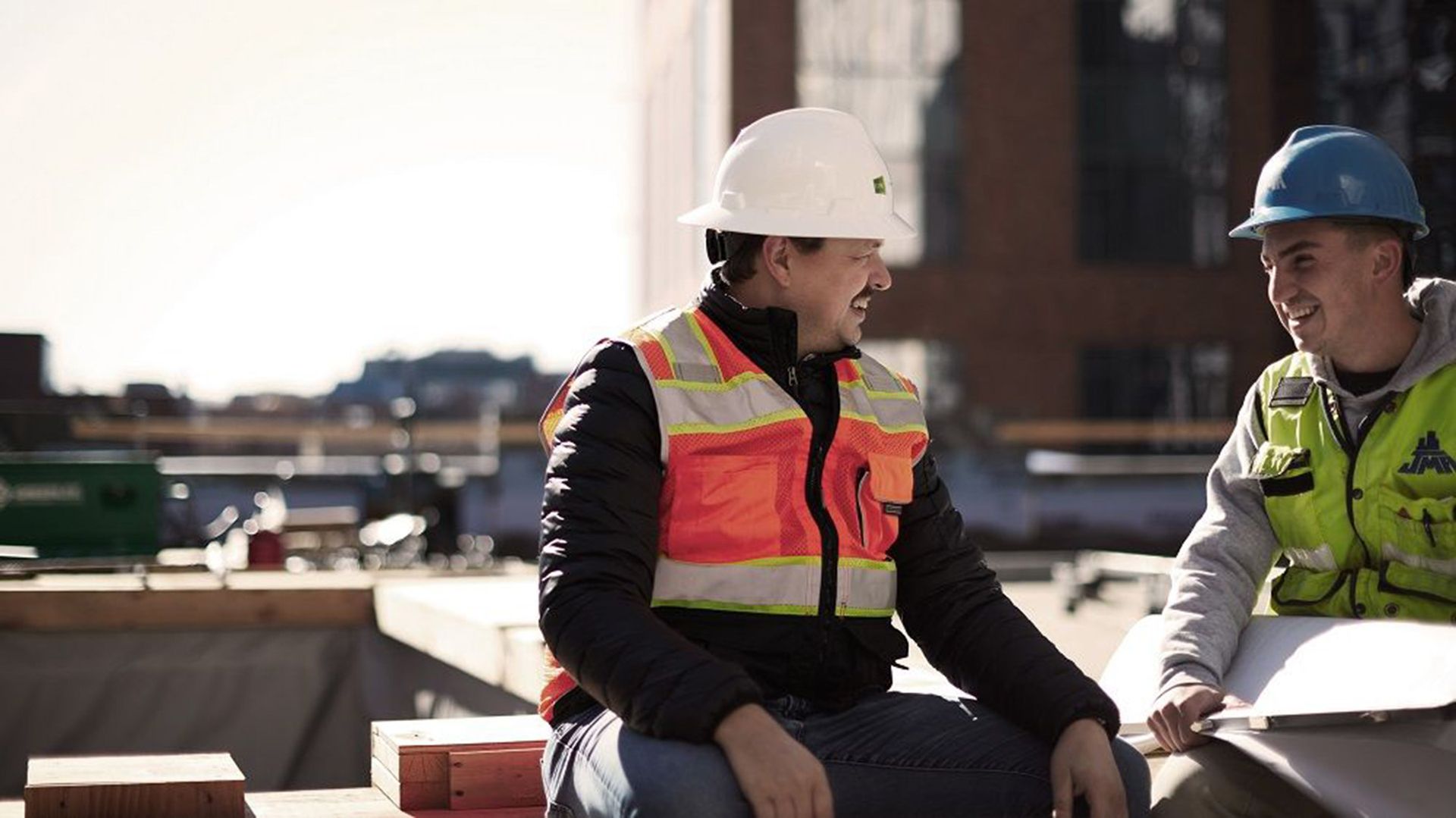 Photo of two construction workers, chatting at a worksite.