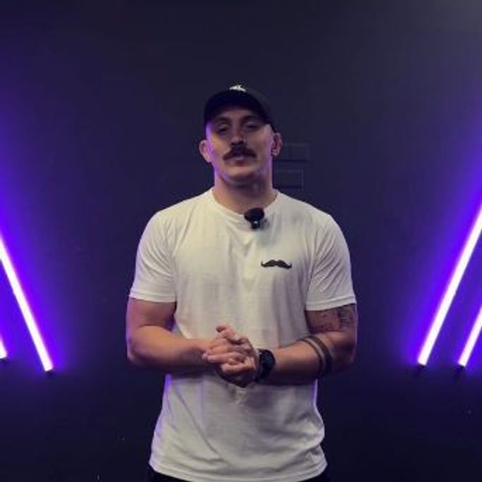 Photo of a man in a Movember-branded polo shirt, about to present on a stage.