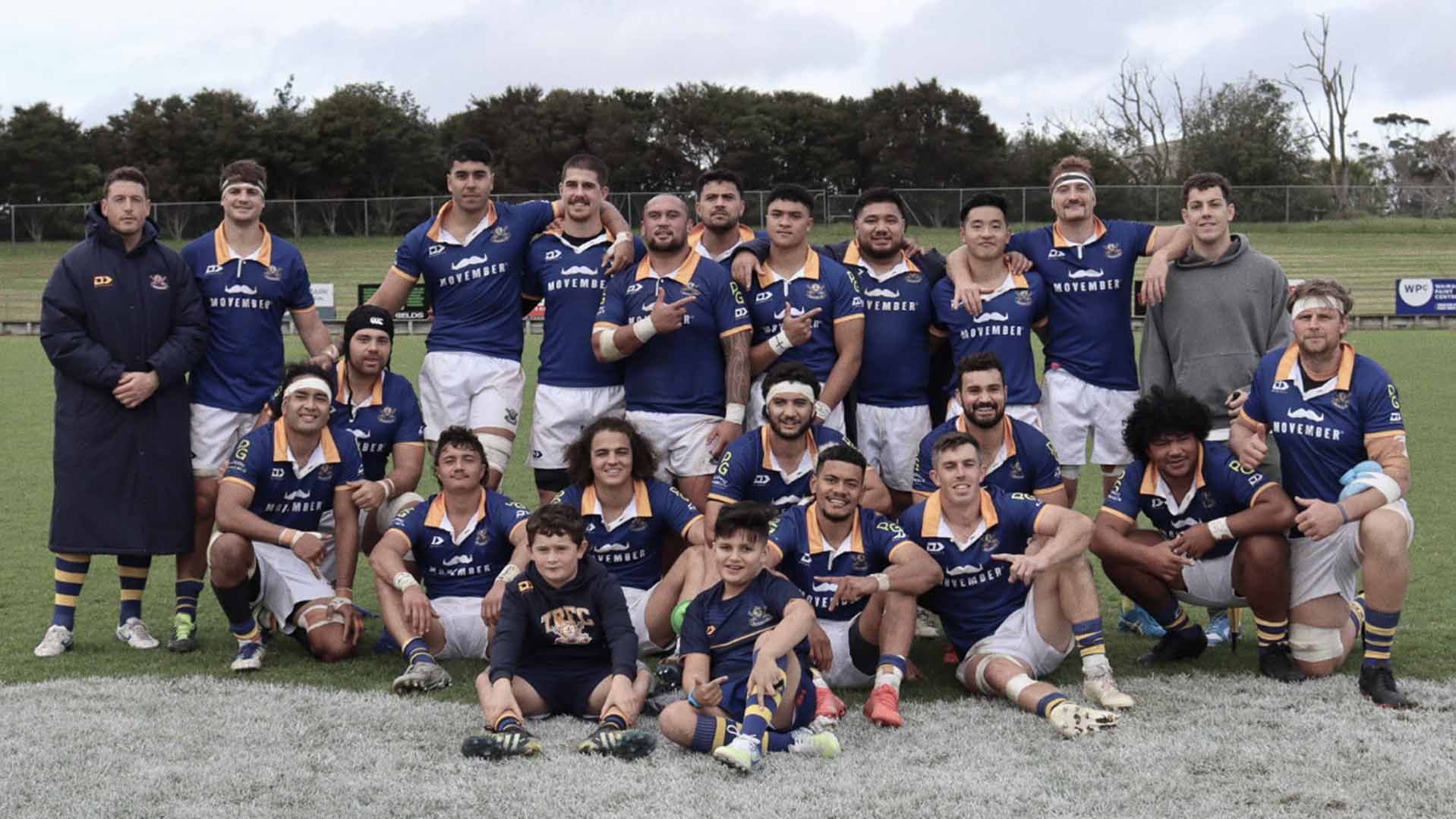 A rugby team posing for the camera, bedecked in Movember Sports Club-branded attire.