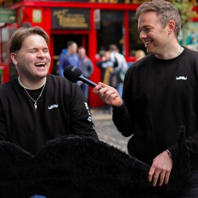 Photo of a man with a microphone interviewing another man on a public street.