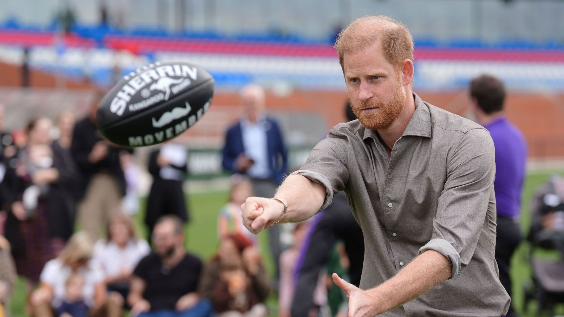 Prince Harry playing footy on AFL field with Movember Sherrin