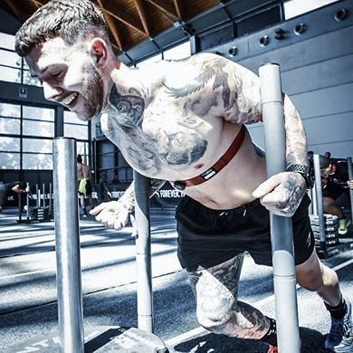 Photo of an exceptionally athletic man in shorts, working out on gym machinery.