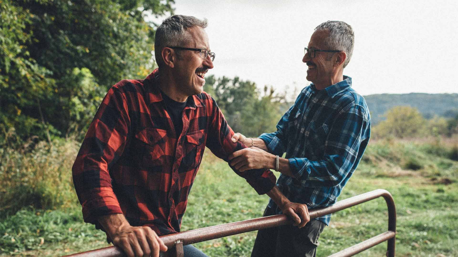 Photo of two smiling men in the countryside.