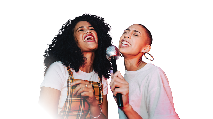 Photo of two women, fervidly singing into a microphone.